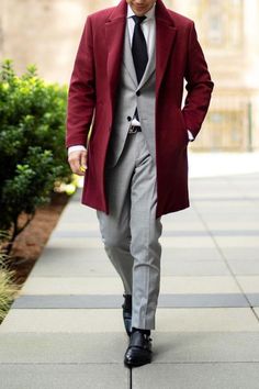 This is a stunning red overcoat paired with a grey three piece suit. This is a wonderful business suit that can make you look fantastic! If you'd like a custom overcoat and custom suit like this, book an appointment with us at Giorgenti New York. #menswear #mensfashion #weddingsuit #menssuits #giorgentiweddings Grey Suit Outfit, Grey Three Piece Suit, Red Overcoat