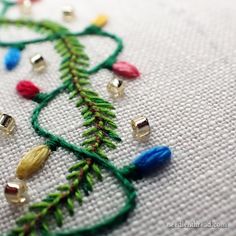 a close up of a piece of embroidery with beads and needles on the bottom half