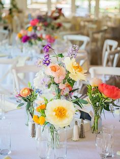 several vases filled with colorful flowers on top of a white tablecloth covered table