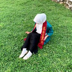 a person sitting in the grass with a scarf around their neck