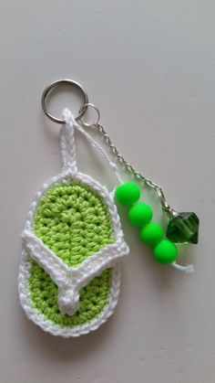 a crocheted keychain with green beads hanging from it's side