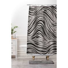 a black and white shower curtain with an abstract design on the front, in a bathroom