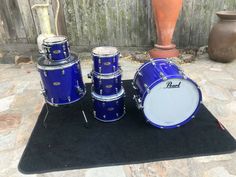 a blue drum set sitting on top of a black mat next to a planter