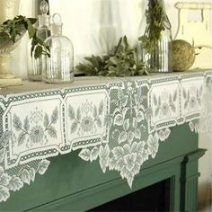 a green mantle with white lace on it and plants in vases next to it