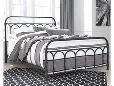 a black and white bed with an intricate iron frame, pillows and blankets on it