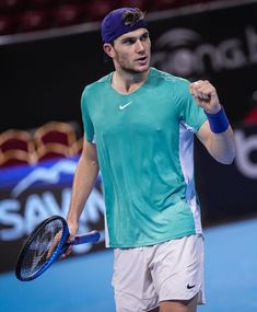 a man holding a tennis racquet on top of a tennis court with his fist in the air