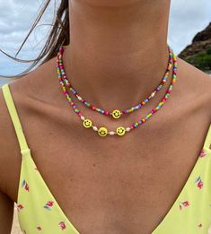 Smiley Face Necklace, Rainbow happy face necklace, multicolor seed bead necklace w/ pearls, beaded necklace, emoji necklace, layering necklace perfect necklace for a beach day or everyday wear! water resistant. this necklace is perfect for everyday wear. all jewelry is handmade.  * handmade jewelry * length: 14-16 inches long with adjustable length  * material: seed beads, pearls, rubber faces *light weight  * Closure: Lobster Claw * chain style: bead * adjustable length  **you can choose between a necklace with 1 or 3 smiley beads & w/without pearls Fun Round Bead Necklaces For Summer, Fun Summer Necklaces With Round Beads, Fun Summer Beaded Necklaces With Round Beads, Cute Colorful Beaded Necklaces For The Beach, Cute Colorful Beaded Necklaces For Beach, Fun Colorful Beaded Necklaces For Summer, Fun Festival Beaded Necklace With Letter Beads, Playful Yellow Beaded Necklaces With Colorful Beads, Playful Yellow Beaded Necklaces