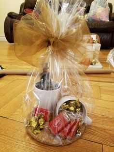 a basket filled with chocolates, candy bars and wrapped in cellophane on top of a wooden floor