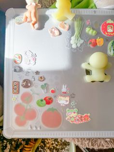 a plastic tray with various stickers on top of it and stuffed animals in the background