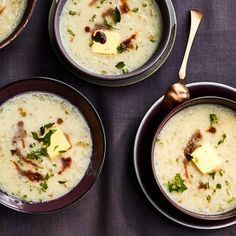 three bowls of soup with cheese and herbs on the side, along with two spoons