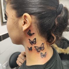 a woman's neck with butterflies tattooed on her left side behind the ear,