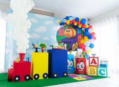 a birthday party with balloons and toys on the floor in front of a wall mural