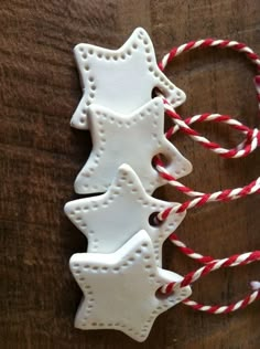 three decorated cookies sitting on top of a wooden table next to red and white twine