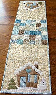 a quilted table runner with a gingerbread house on the front and snowman on the back