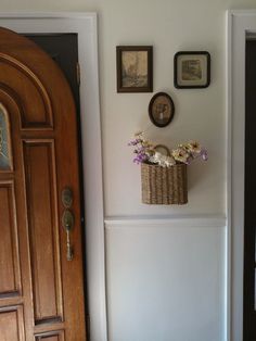 there is a basket with flowers in it on the wall next to an open door