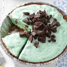 a pie with green frosting and chocolate chips on top is sitting on a table