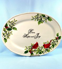 a white platter with red birds and holly on it