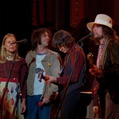 three people standing next to each other with microphones in their hands and one person holding a guitar