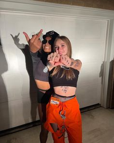 two women standing in front of a garage door making the peace sign with their hands