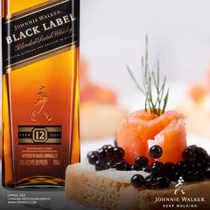 a bottle of black label wine next to some food on a white plate with olives