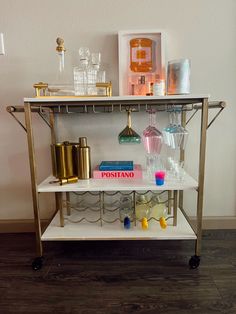 a shelf with glasses, books and other items sitting on it's sides in front of a white wall