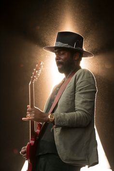 a man wearing a hat and holding a guitar