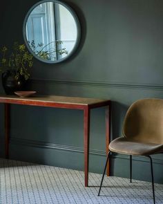 two chairs and a table in front of a round mirror on the wall next to a potted plant