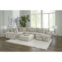 a living room with a large sectional couch and white rugs on the hardwood floor