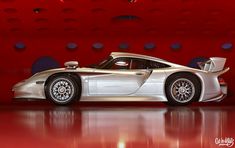 a silver sports car sitting on top of a red floor