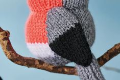 a knitted bird sitting on top of a tree branch