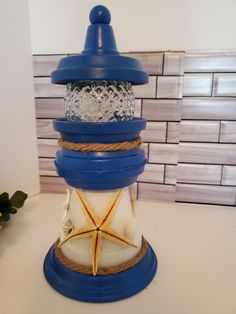 a blue and white candle holder with a starfish on the top, sitting on a table