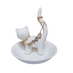 a white cat figurine with a gold chain around it's neck on a plate