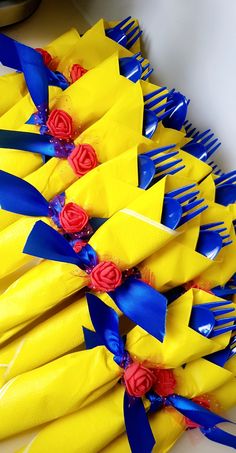 a bunch of yellow and blue plastic forks with red roses on the ends are lined up