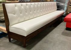 a white leather couch sitting on top of a hard wood floor next to a red chair