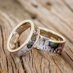 two wedding rings sitting on top of a wooden table with moss growing in the middle