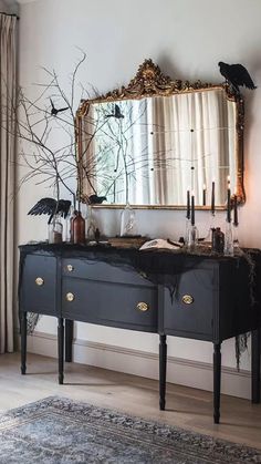 a black dresser and mirror in a living room with candles on the sideboard, halloween decorations