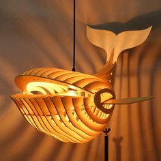 a lamp that looks like a fish is hanging from the ceiling in front of a wall