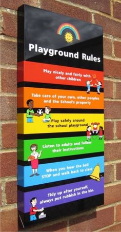 a playground rules sign mounted to the side of a brick wall