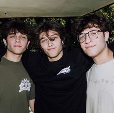 three young men standing next to each other with their arms around one another and looking at the camera