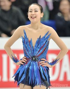 a female figure skating in a competition wearing blue and red dress with feathers on it