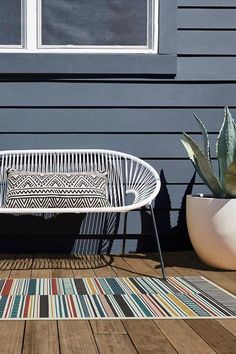 a white bench sitting on top of a wooden floor next to a potted plant