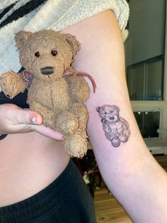 a small teddy bear tattoo on the right side of her left arm, next to a woman's stomach