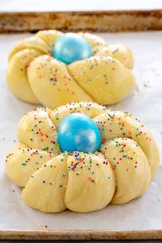 two buns with sprinkles and blue eggs in them on a baking sheet