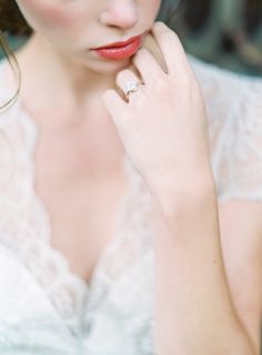 a woman in a white dress with a diamond ring on her finger and red lips