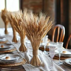 the table is set with wheat stalks in vases and place settings for dinner guests