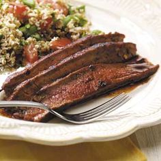 a white plate topped with meat, rice and veggies next to a fork