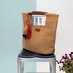 a bag sitting on top of a chair next to a vase with flowers in it