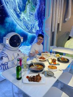 two people sitting at a table with food in front of an image of the earth