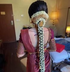 a woman in a red sari with pearls on her head and braids tied around her neck