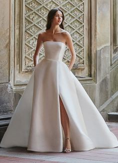 a woman in a white wedding dress posing for the camera with her hand on her hip